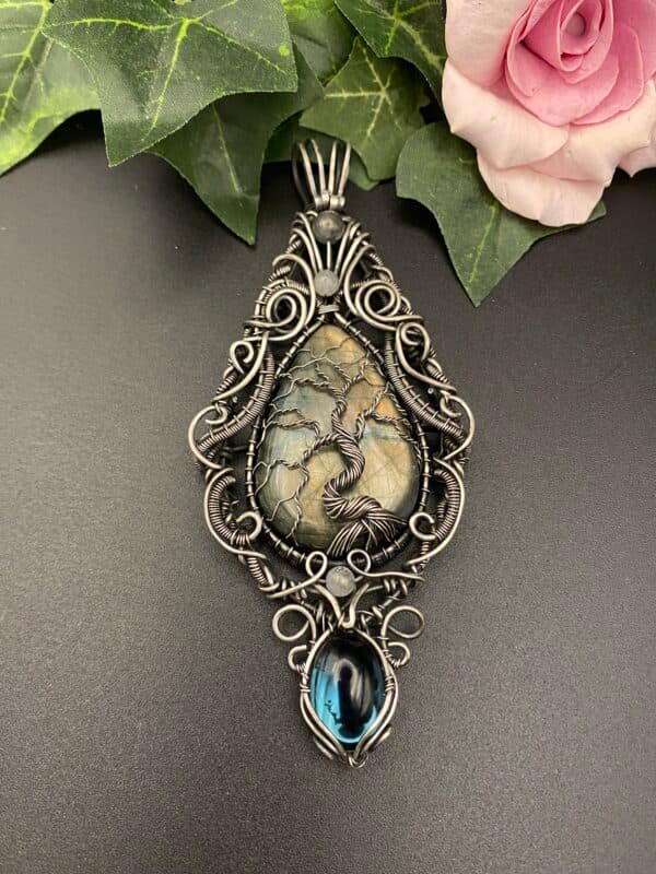 Large teardrop labradorite Tree of Life pendant on a measuring mat showing detailed silver wire weaving and a hanging Preciosa glass cabochon.