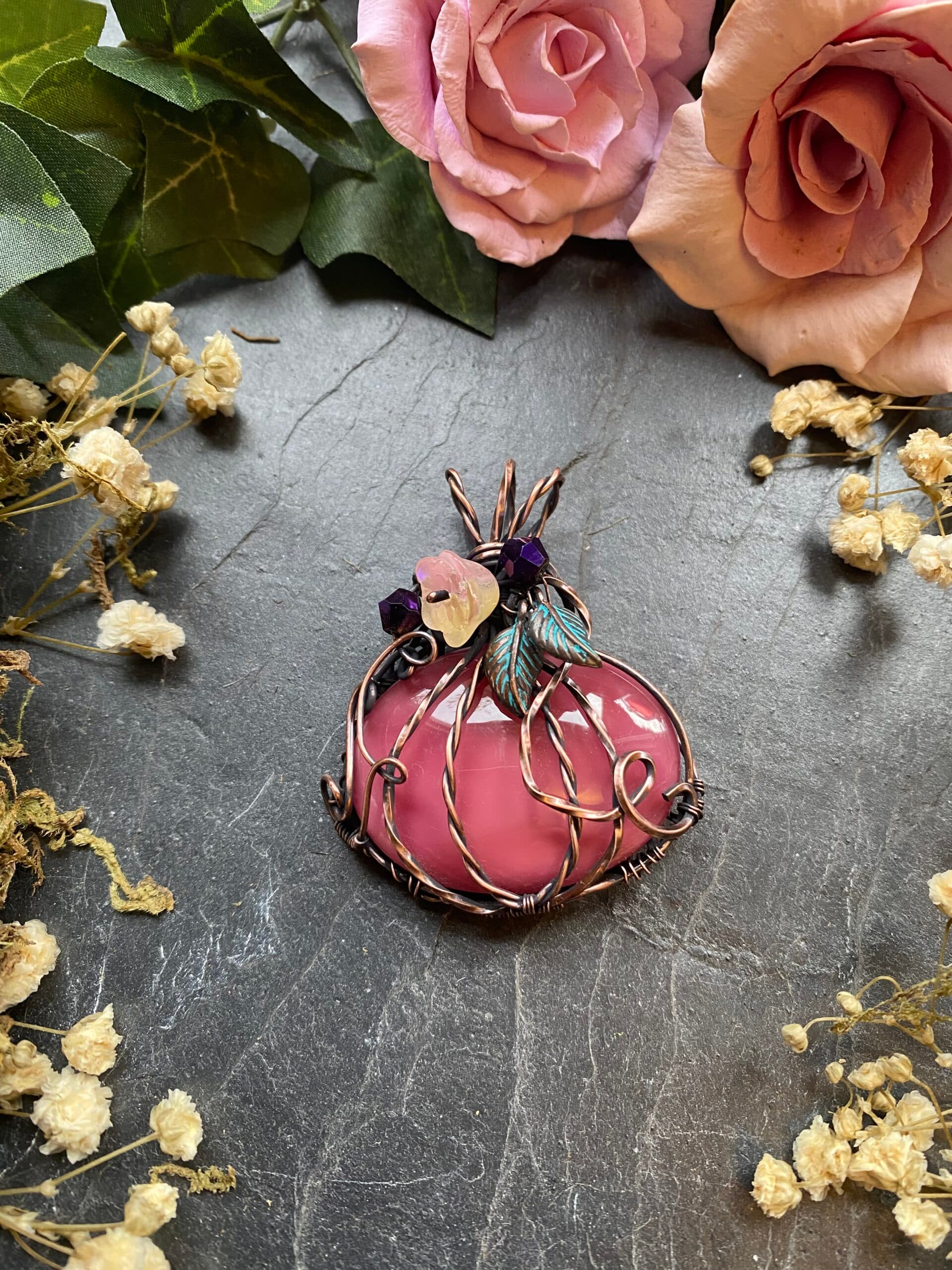 Handmade copper wire wrapped pumpkin pendant featuring a dusky pink vintage Preciosa glass cabochon with curling copper vines and decorative stem.