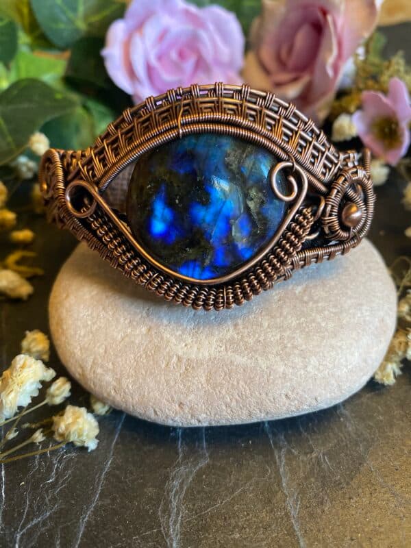 Front view of handmade labradorite eye cuff bracelet with brilliant blue flash gemstone, antiqued copper weaving and decorative scrollwork.