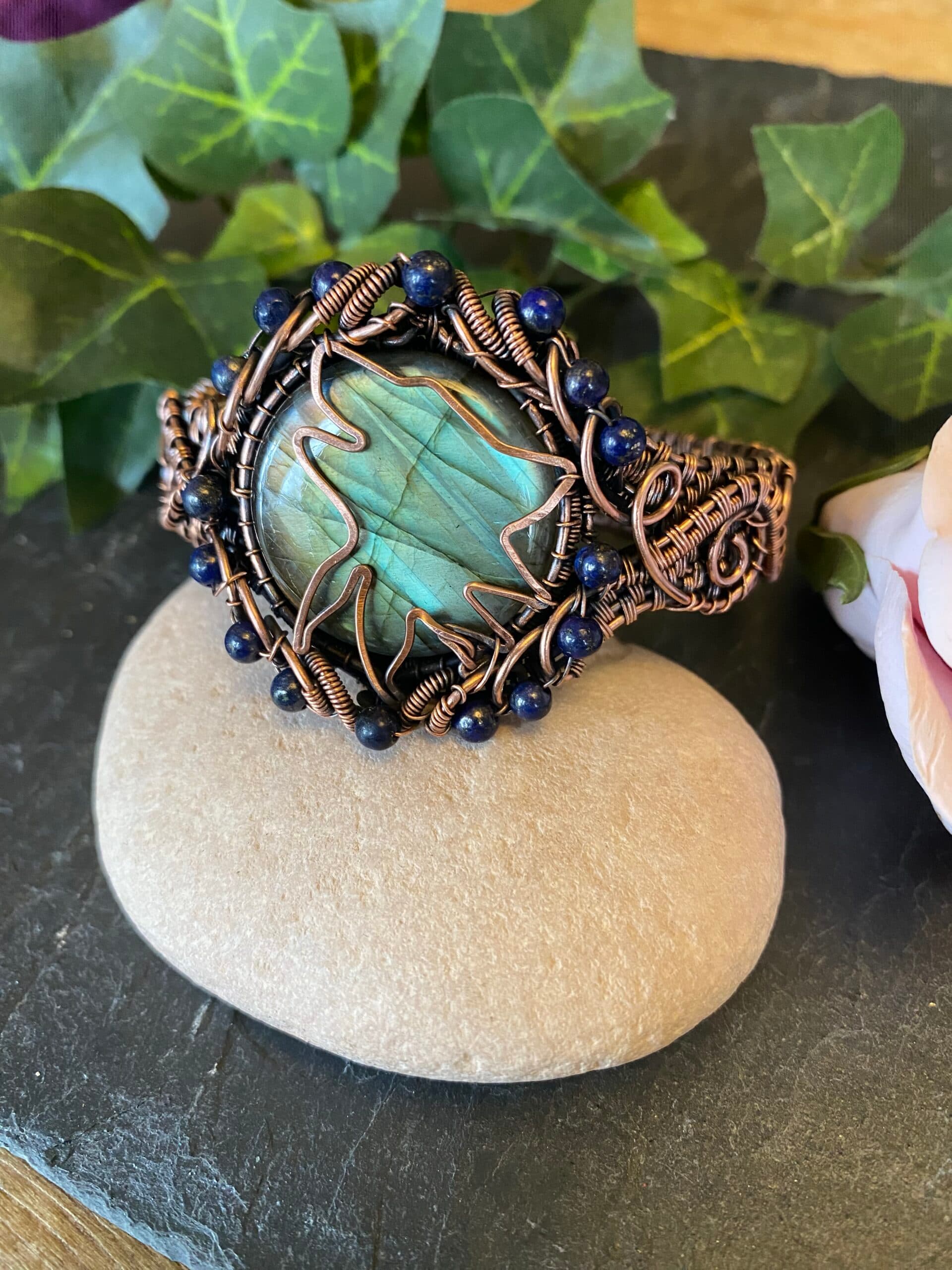 Handwoven copper wolf head cuff bracelet with labradorite and lapis lazuli beads Copper wolf head cuff showing woven wire detail and gemstone centerpiece Handwoven copper cuff bracelet with hammered wolf symbol and mystical stones