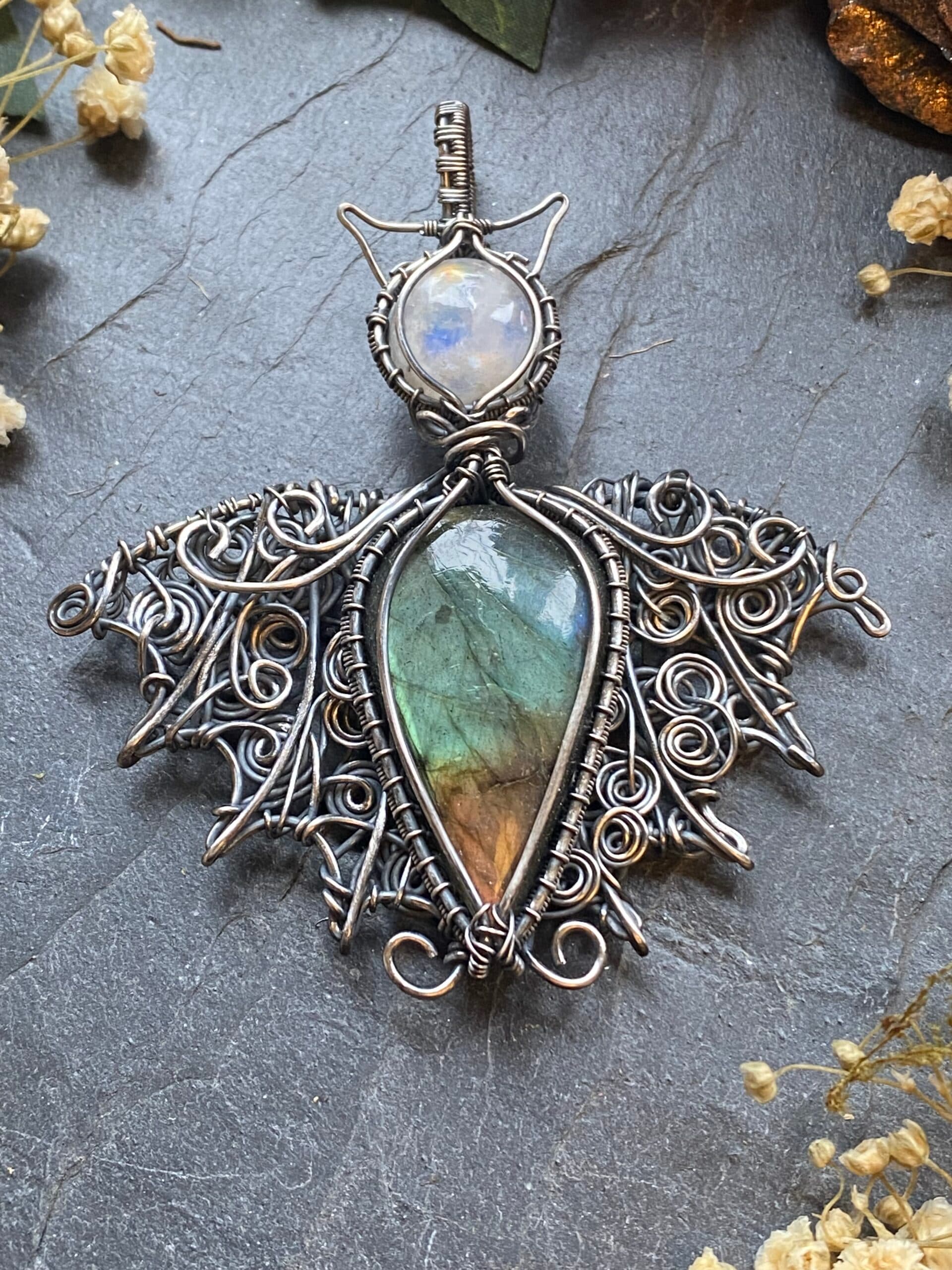 Handmade labradorite bat pendant with green, gold and brown flash gemstone body, Rainbow Moonstone head and ornate silver filled wire woven wings.