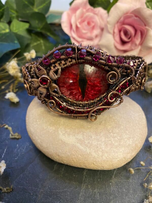 Handmade red dragon eye cuff bracelet with intricate copper wire weaving, red Swarovski crystals and a hand-painted red and pink dragon eye.