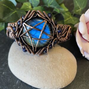 Handwoven copper pentagram cuff bracelet with hammered symbol and lapis lazuli beads Copper pentagram cuff bracelet showing woven wire detail and blue beads Handwoven copper cuff bracelet with antiqued pentagram and lapis accents