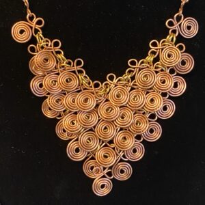 Copper chain mail necklace with spiral wire components and brass jump rings in a fluid V shape